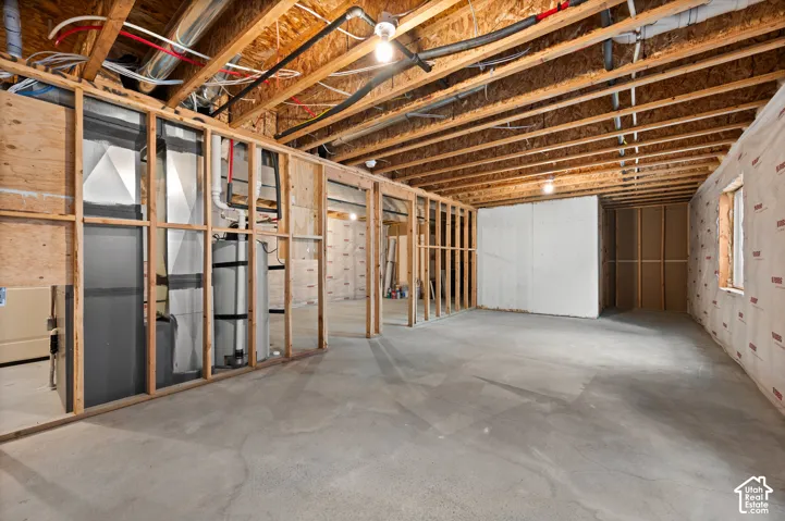 Unfinished lower level featuring exposed wood joist ceilings, concrete flooring, stud-framed walls, and integrated mechanical systems