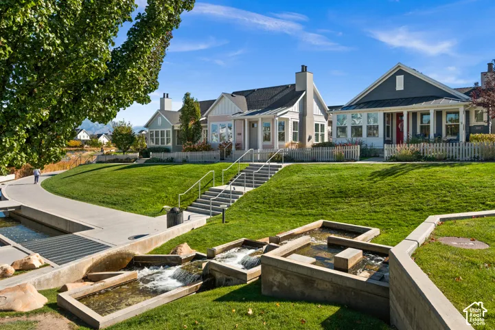 Exterior featuring multi-gabled rooflines, fiber cement siding, white picket fencing, stepped concrete hardscaping, and a tiered water feature