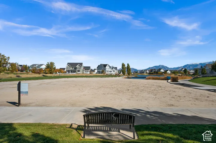 Expansive sandy recreation area featuring paved pedestrian pathways, waterfront access, and mountain backdrop