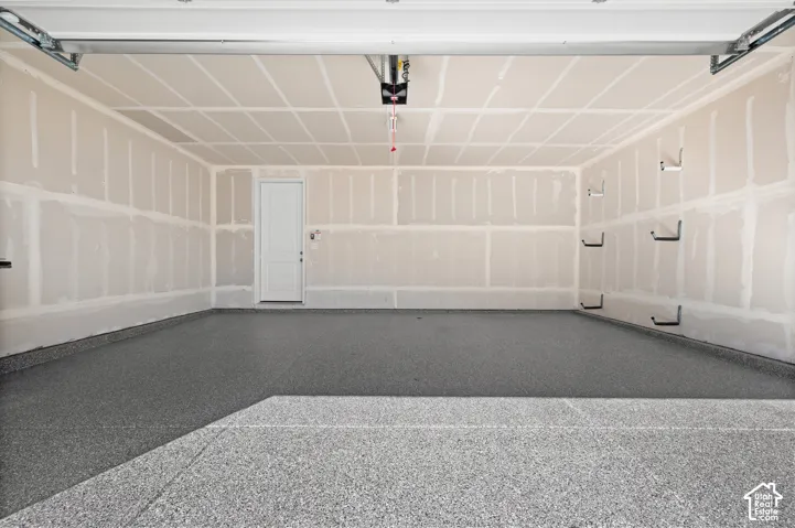 Attached multi-car garage featuring epoxy-coated flooring, drywalled interior, and an automated overhead door opener