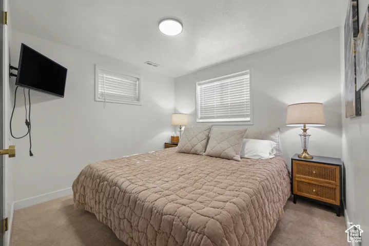 Neutral wall tones, wall-to-wall carpeting, and dual windows with horizontal blinds