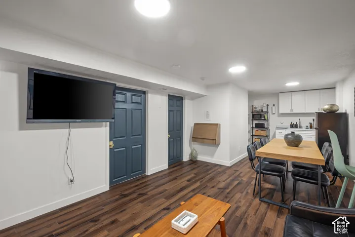 Wood-finish flooring, recessed ceiling lighting, and a kitchenette area featuring white cabinetry and a white countertop