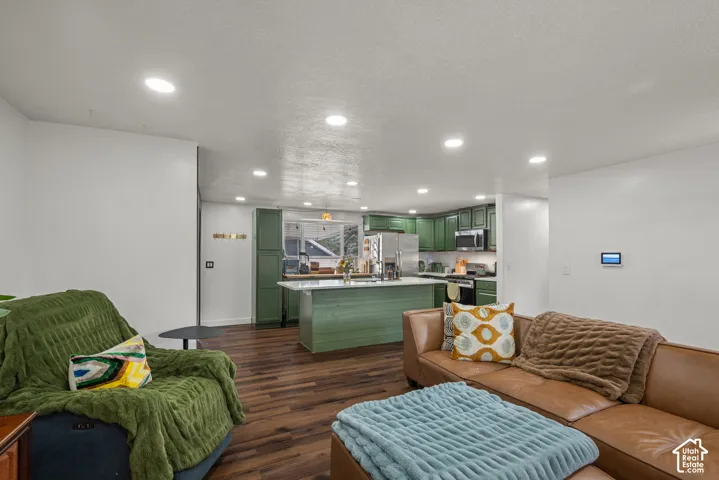 Kitchen featuring green cabinetry, a central island with a white countertop, wood-finish flooring, and recessed ceiling lighting