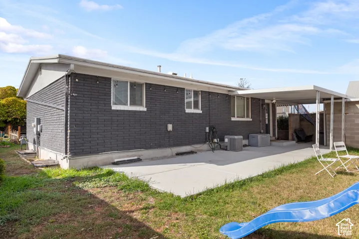 Exterior featuring painted brick masonry, concrete patio, covered carport, and horizontal aluminum siding