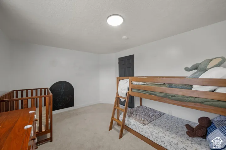 Neutral-toned interior space featuring wall-to-wall carpeting, an arched built-in wall feature, flush-mount ceiling lighting, and a dark-finished interior door