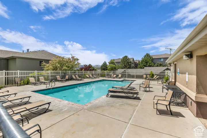 Outdoor swimming pool featuring a concrete deck and decorative brick coping, enclosed by white vinyl fencing