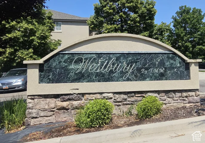 Custom signage featuring a dark, polished stone panel with a curved stucco crown, mounted on a stacked-stone base with integrated landscaping