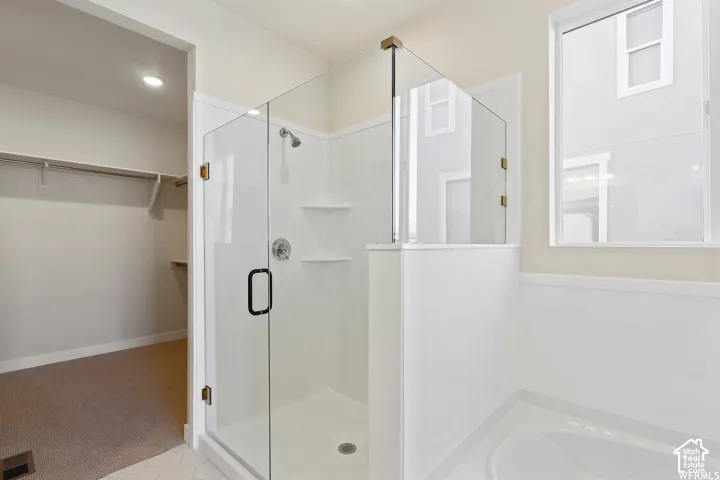 Walk-in shower featuring a frameless glass enclosure, built-in corner shelving, and chrome hardware, with an adjoining closet area containing built-in shelving