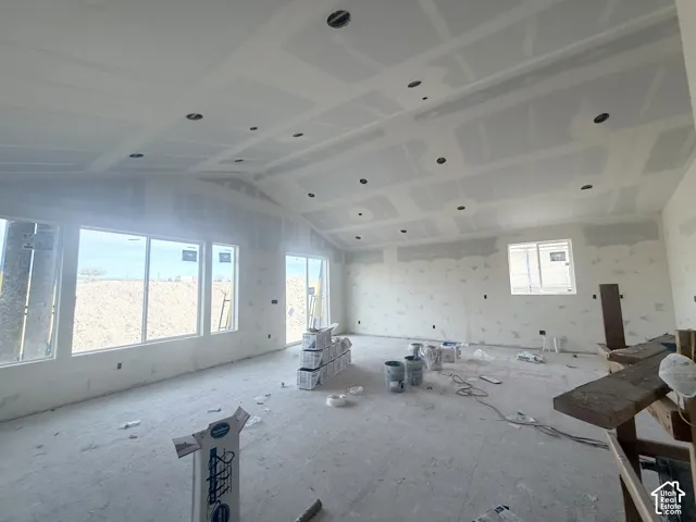 Vaulted ceilings featuring recessed lighting, expansive windows, and a sliding glass door