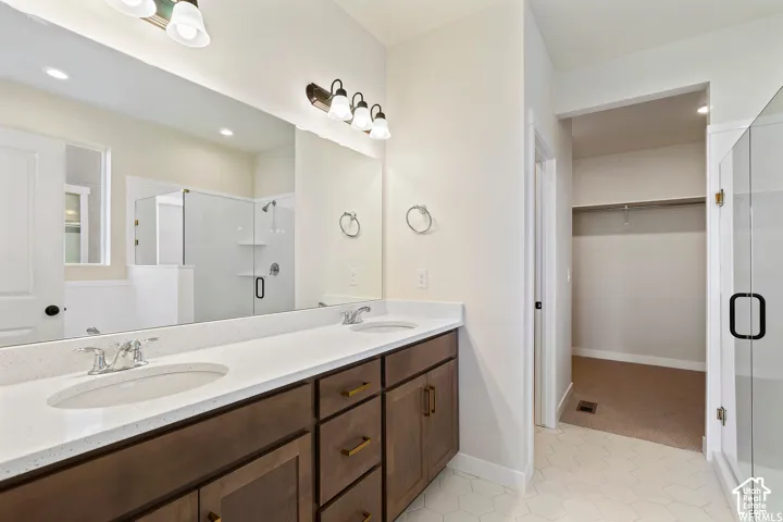 Double vanity featuring wood-finish cabinetry, white solid-surface countertops, integrated dual sinks, and full-width mirrors