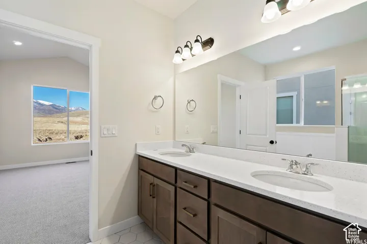 Double vanity featuring an expansive countertop, undermount sinks, wood-finish cabinetry, and wall-mounted multi-bulb light fixtures