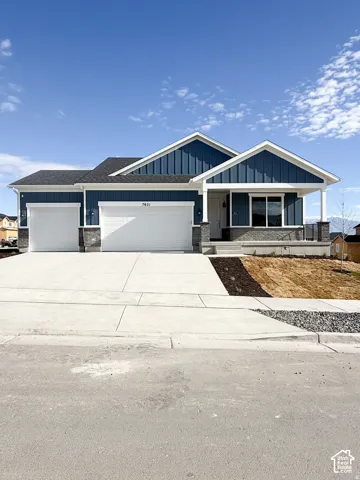 Exterior featuring blue vertical siding, stone masonry accents, a three-car garage, and a covered front porch