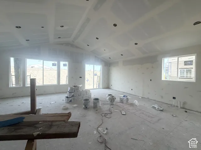 Vaulted ceilings featuring recessed lighting, expansive multi-panel windows, and a sliding glass door