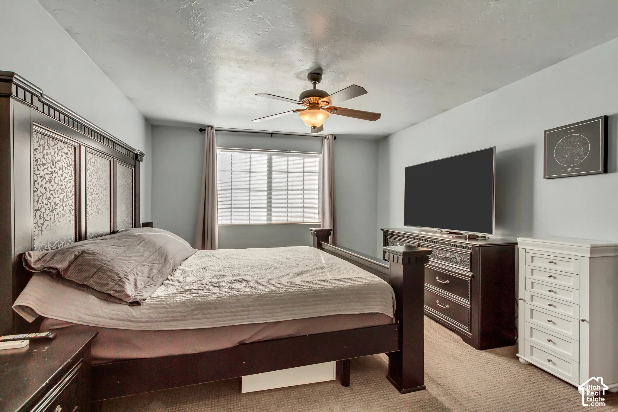 Bedroom featuring neutral-toned carpeting, grid-patterned window, and a ceiling fan with integrated lighting