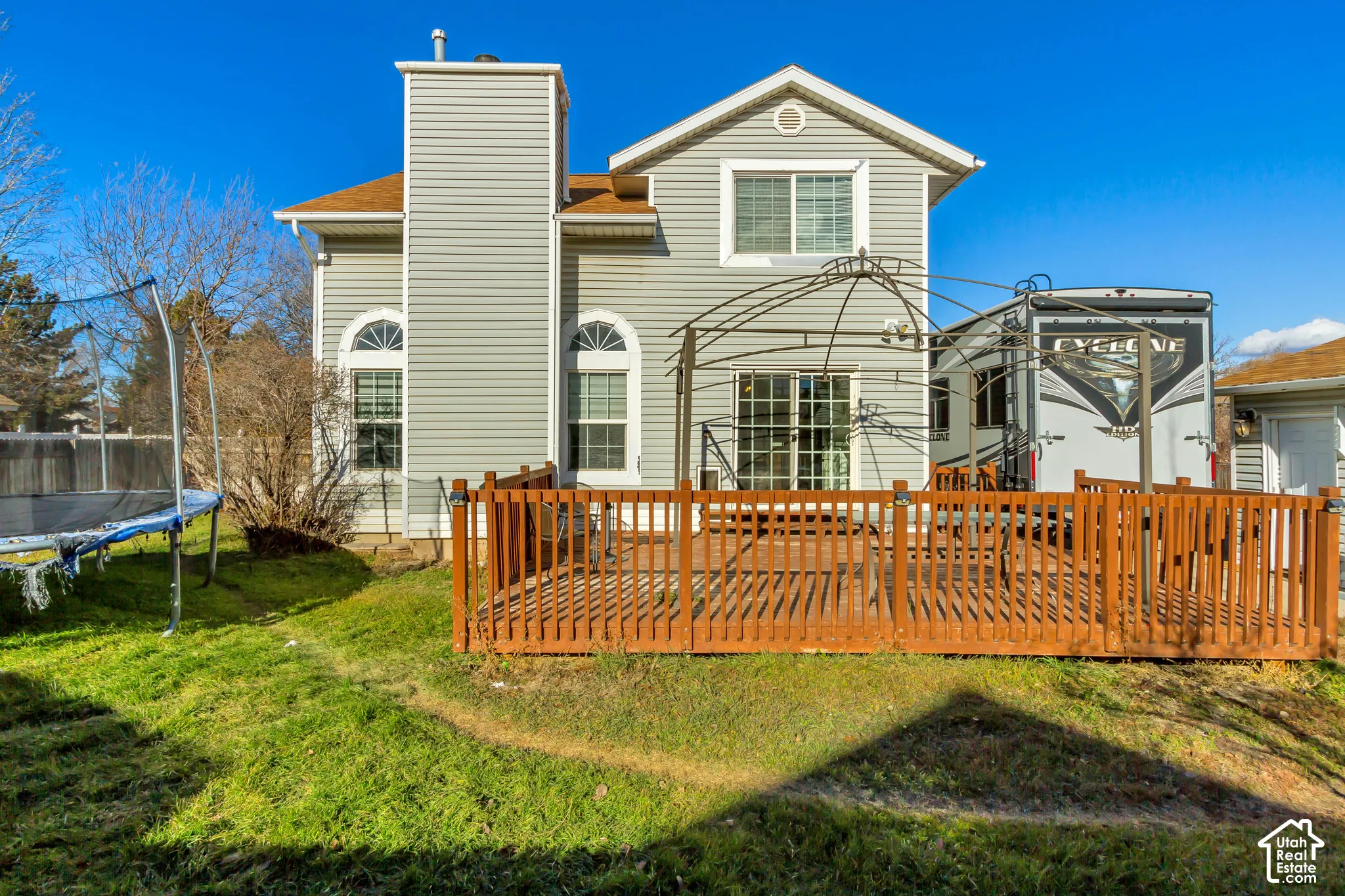 Exterior featuring vinyl siding, a multi-story gable roofline, arched window detailing, and a raised wooden deck