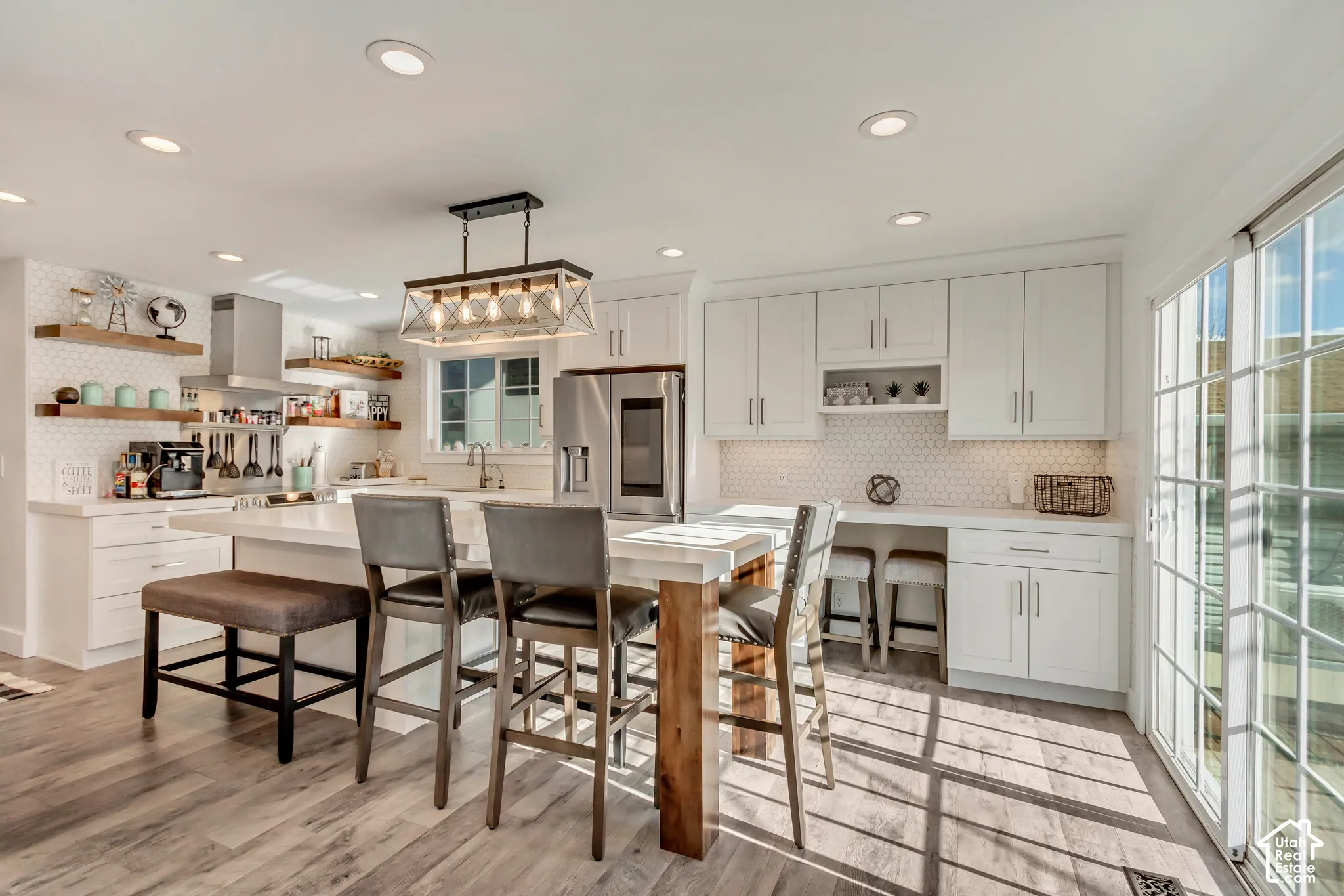 Kitchen featuring white cabinetry, wood-finish flooring, a kitchen island with stone-surface countertop, floating wood shelving, and a rectangular multi-light pendant fixture