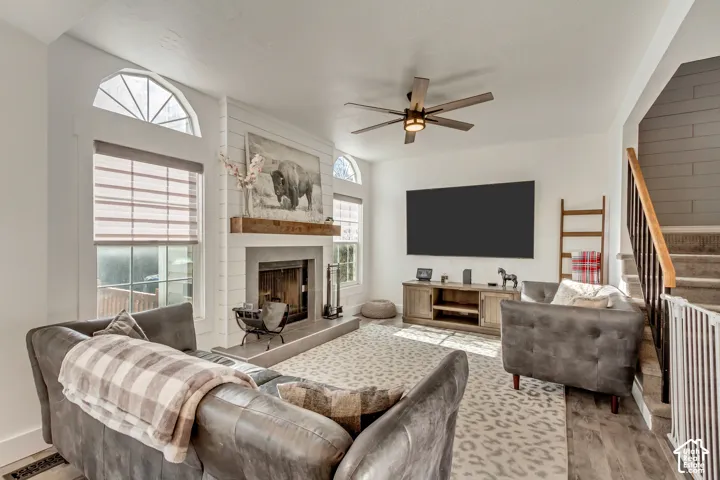 Living area featuring a fireplace with a horizontal shiplap surround, natural wood mantel, arched transom windows, and a ceiling fan