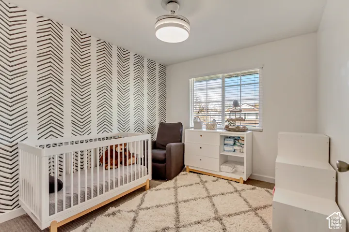 Room featuring a patterned accent wall, neutral carpeting, horizontal window blinds, and a modern integrated ceiling fan with a light fixture