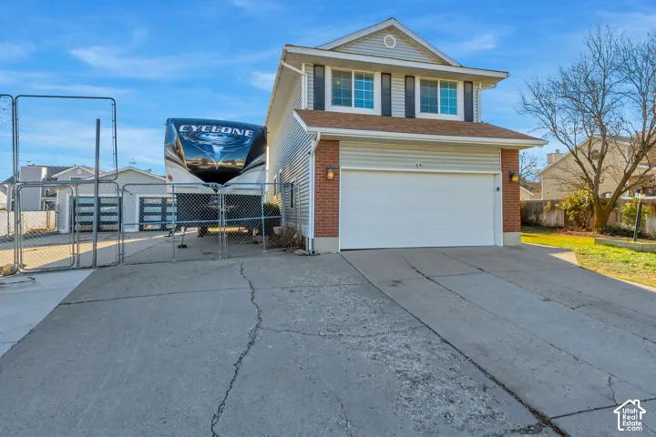 Two-story residence with a combined brick and horizontal siding exterior, featuring a two-car garage and gated side parking area
