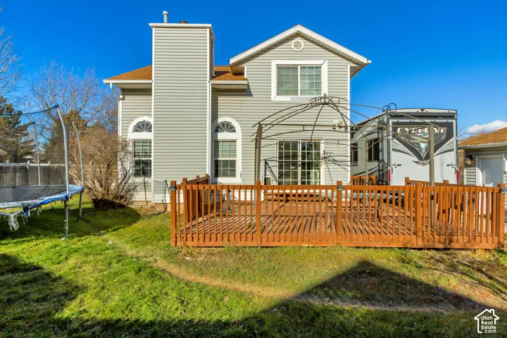 Exterior featuring vinyl siding, a multi-story gable roofline, arched window detailing, and a raised wooden deck