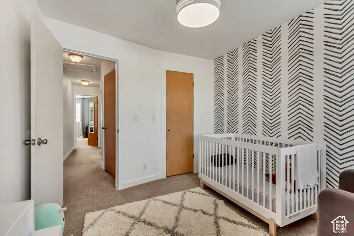 Room featuring a bold geometric accent wall, neutral carpeting, and a flush-mount ceiling light fixture