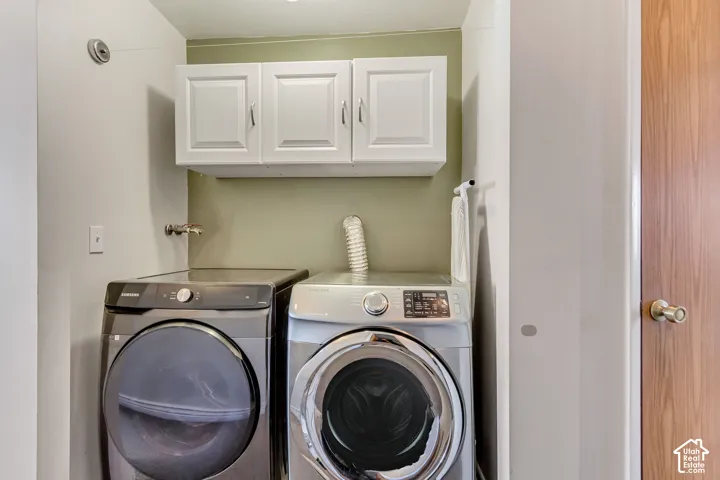 Laundry area featuring white shaker-style wall-mounted cabinetry and a solid-core wood-finish door