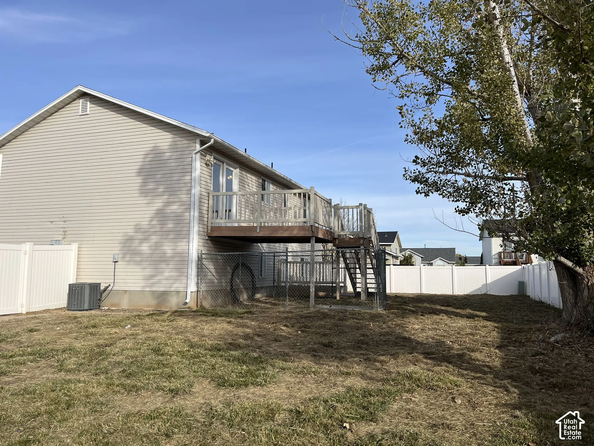 Elevated wood deck with stairs, vinyl siding, and white vinyl privacy fencing enclosing the rear yard