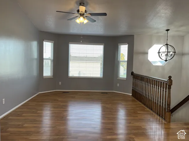 Wood-finish flooring, vaulted ceilings, bay window configuration, wooden staircase railing, and metal orb chandelier