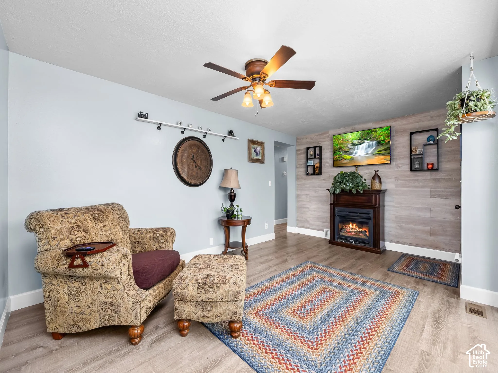 Living area featuring wood-finish flooring, a wood-panel accent wall, and a built-in fireplace with a mantel