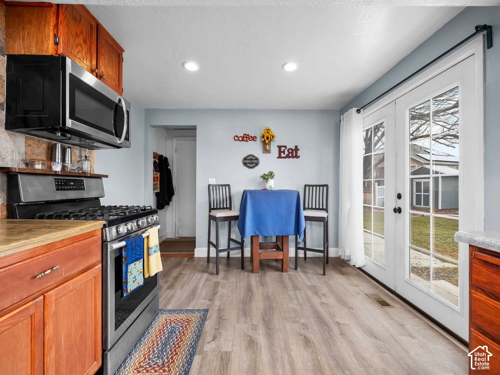 Kitchen featuring wood-finish cabinetry, stainless steel gas range, built-in microwave, recessed lighting, and double glass-paned doors