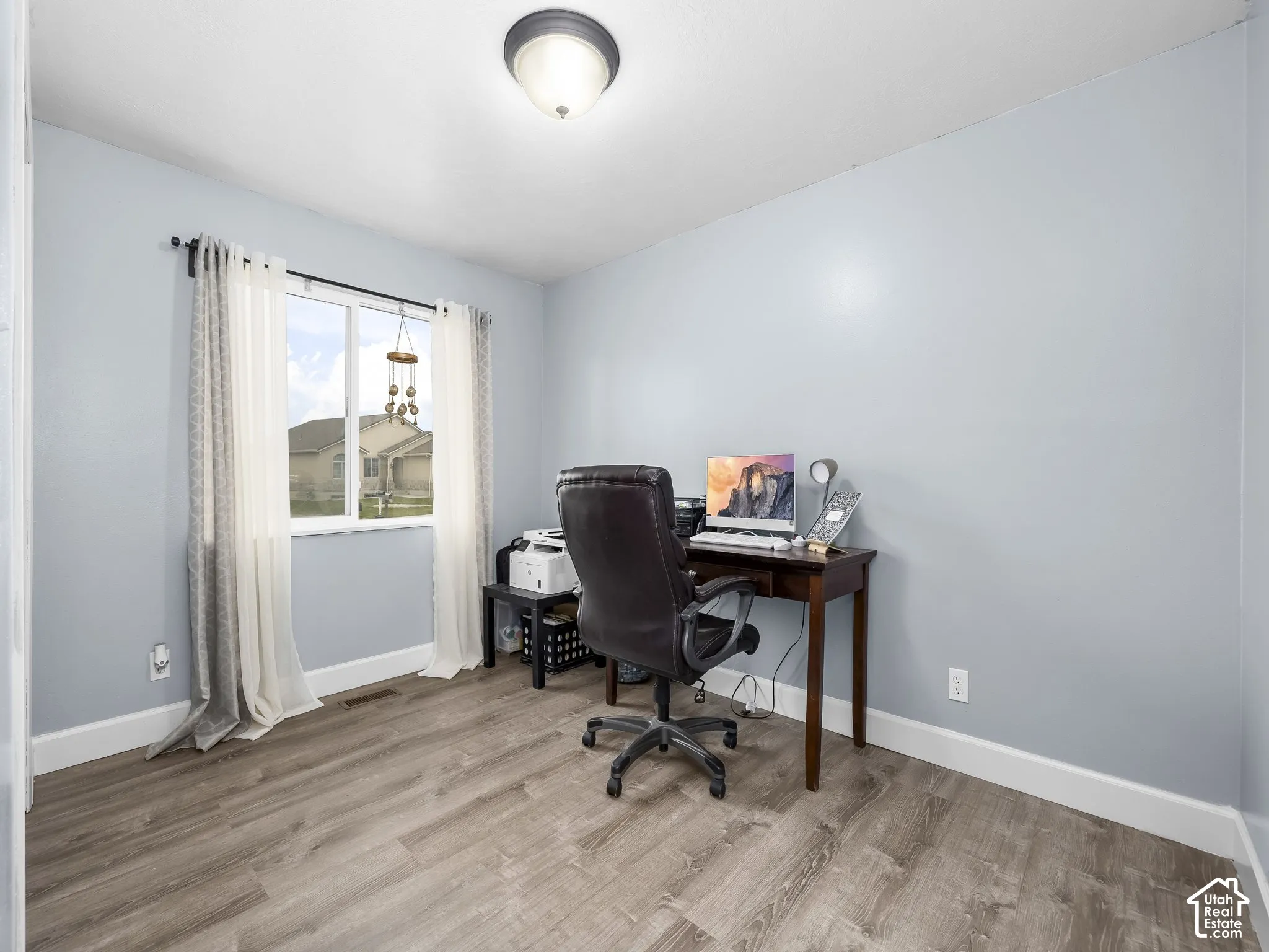 Room featuring wood-finish flooring, a large sliding window, and a central flush-mount light fixture