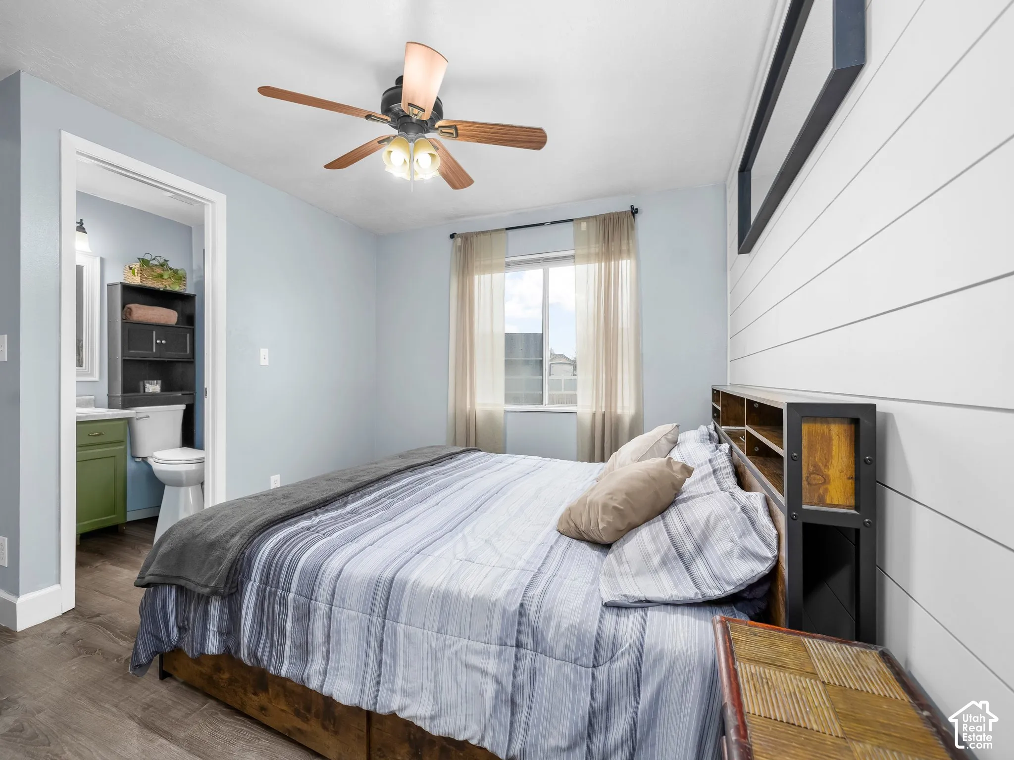 Horizontal shiplap accent wall, wood-finish flooring, and a multi-light ceiling fan