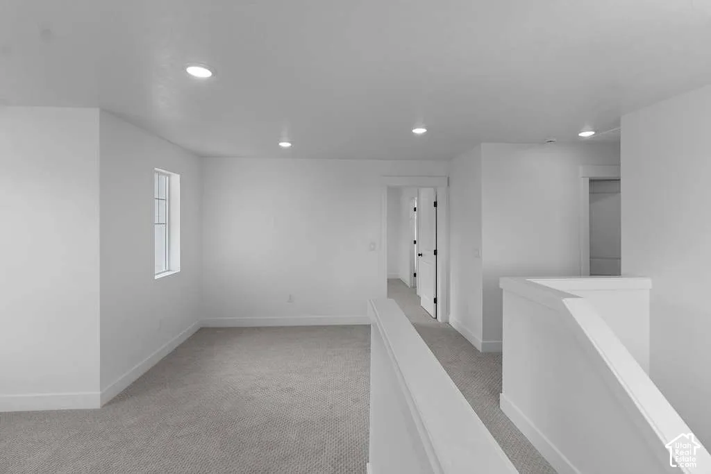 Neutral-toned wall-to-wall carpeting, recessed ceiling lighting, and crisp white wall finishes