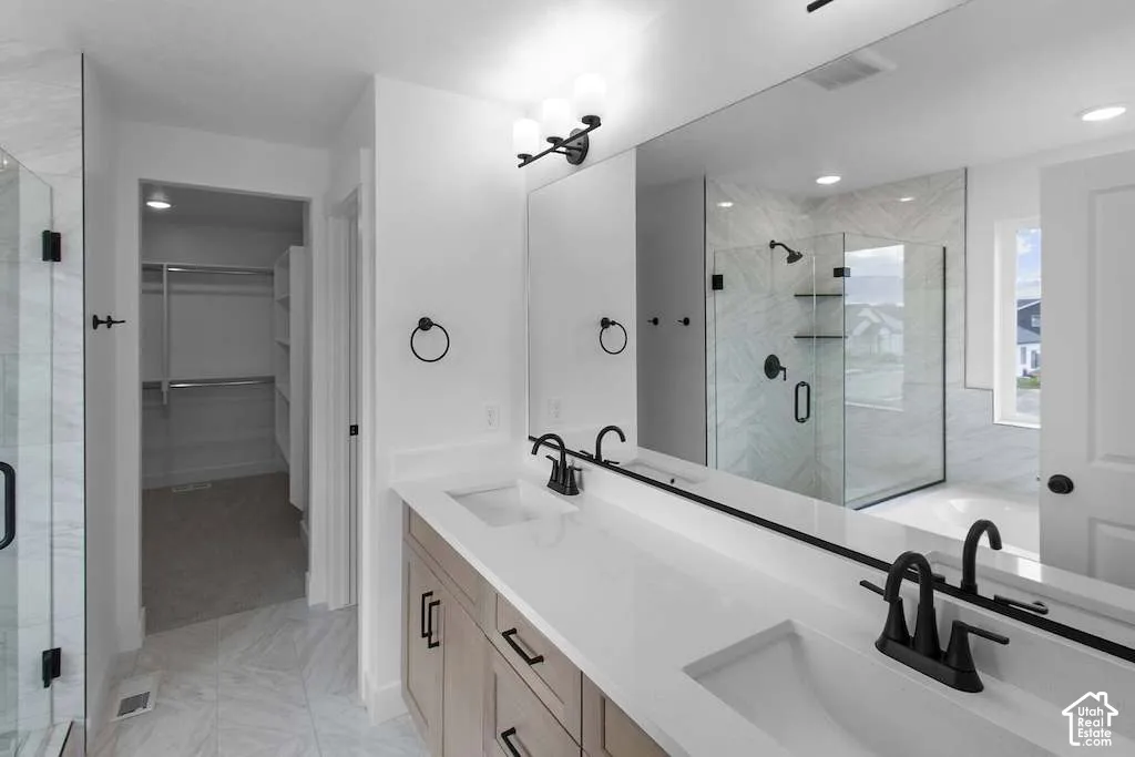 Dual-sink vanity with quartz countertops, matte black plumbing fixtures, glass-enclosed shower with tile surround, and expansive full-width vanity mirror