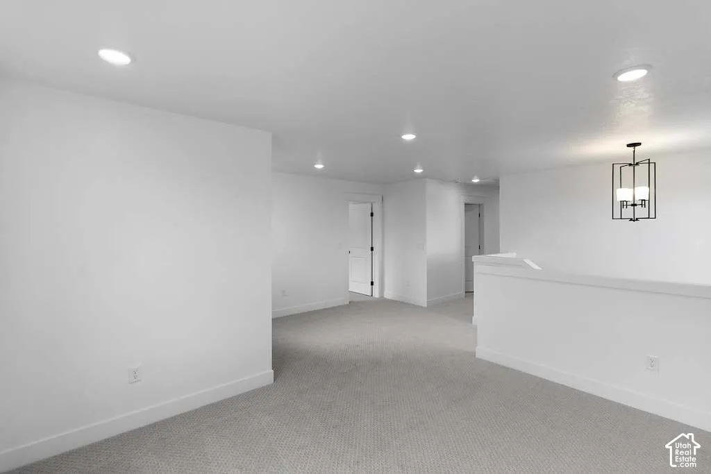 Neutral-toned carpeted flooring, recessed lighting, and a geometric metal chandelier featuring four candelabra-style bulbs
