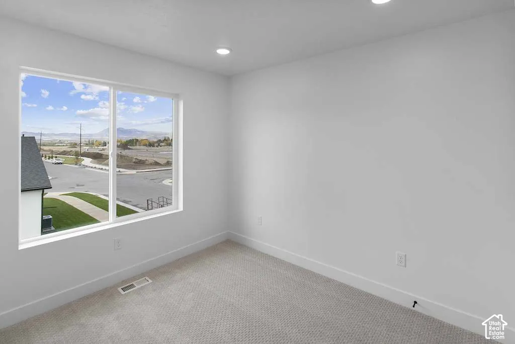 Neutral interior featuring light-toned wall-to-wall carpeting, recessed ceiling lighting, and a large slider window with a mountainous backdrop