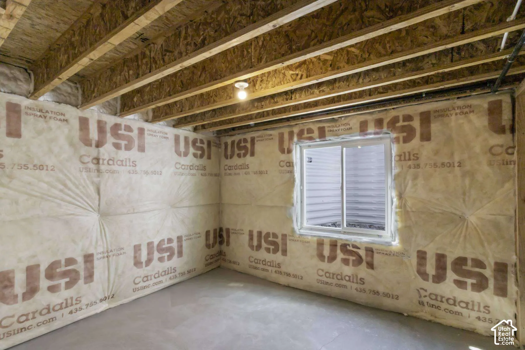 Unfinished utility space featuring exposed wood joist ceilings, concrete flooring, perimeter spray foam insulation, and a sliding egress window