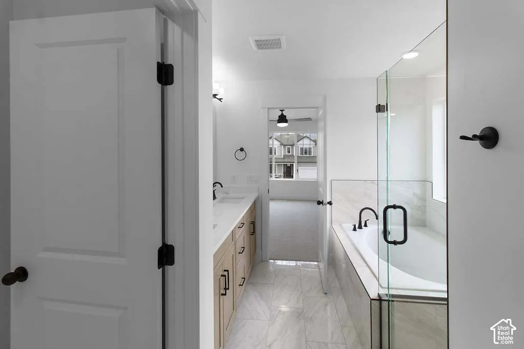 Bathroom featuring a dual-sink vanity with light-tone cabinetry, quartz countertops, matte black fixtures, tile flooring, and a glass-enclosed soaking tub
