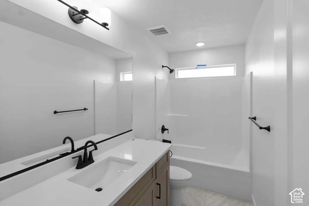 Bathroom featuring a single-sink vanity with a solid-surface countertop, matte black fixtures, a large wall-mounted mirror, and a combination tub and shower surround