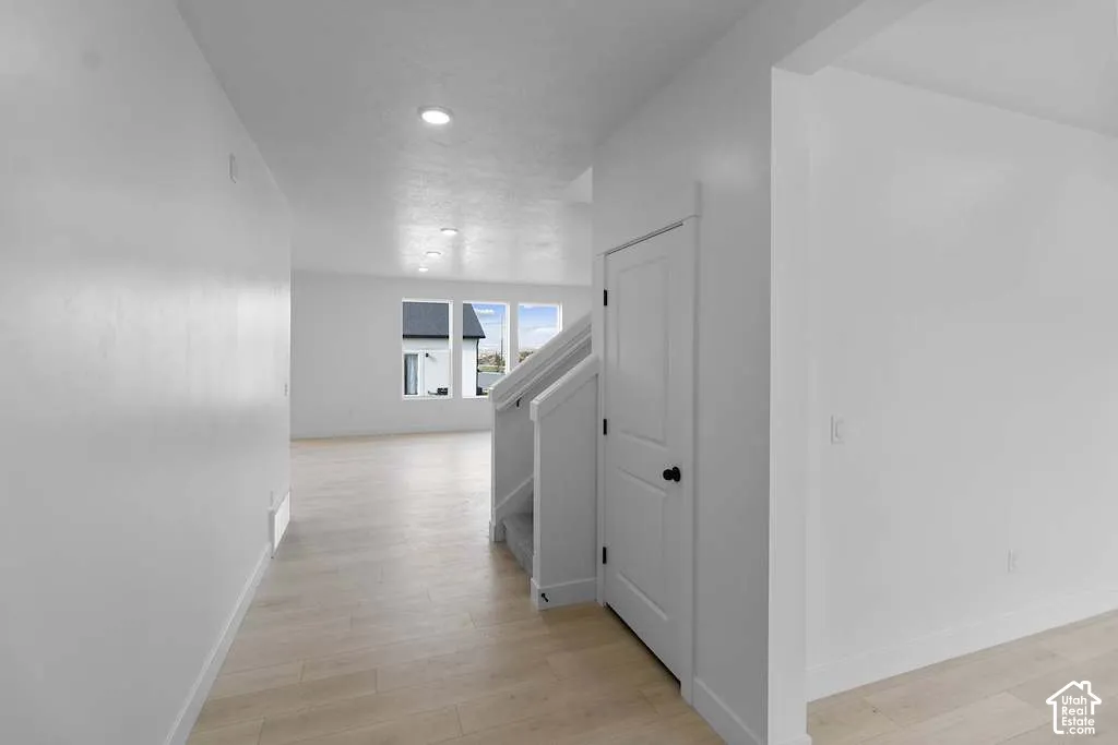 Interior featuring light-toned wood-finish flooring, recessed lighting, and a paneled interior door with matte black hardware