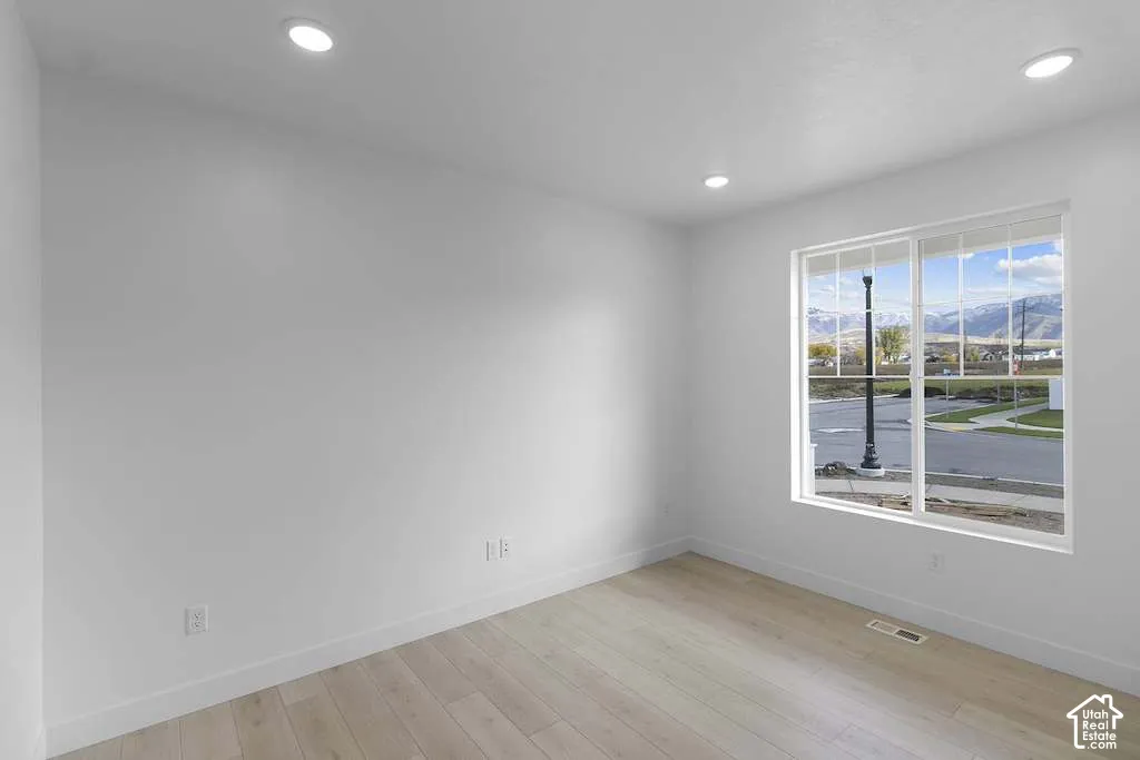 Room featuring wood-finish flooring, recessed lighting, and a large window with mountain scenery