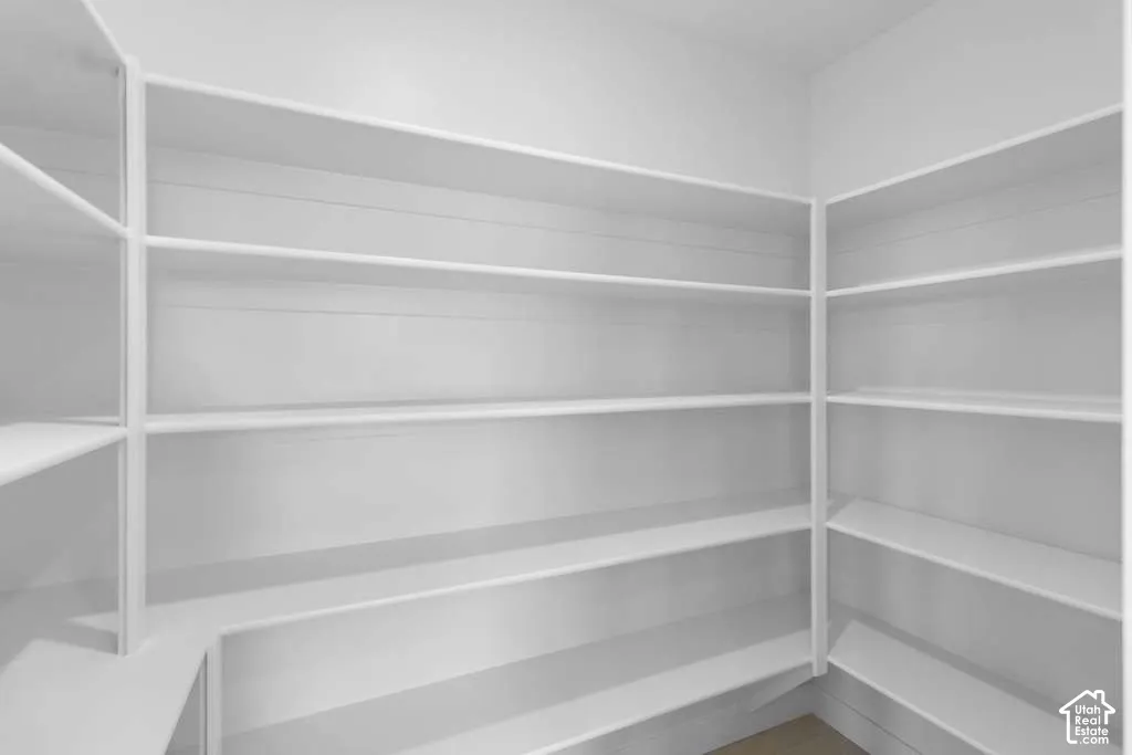 Walk-in storage area featuring floor-to-ceiling white shelving and horizontal plank-style wall paneling