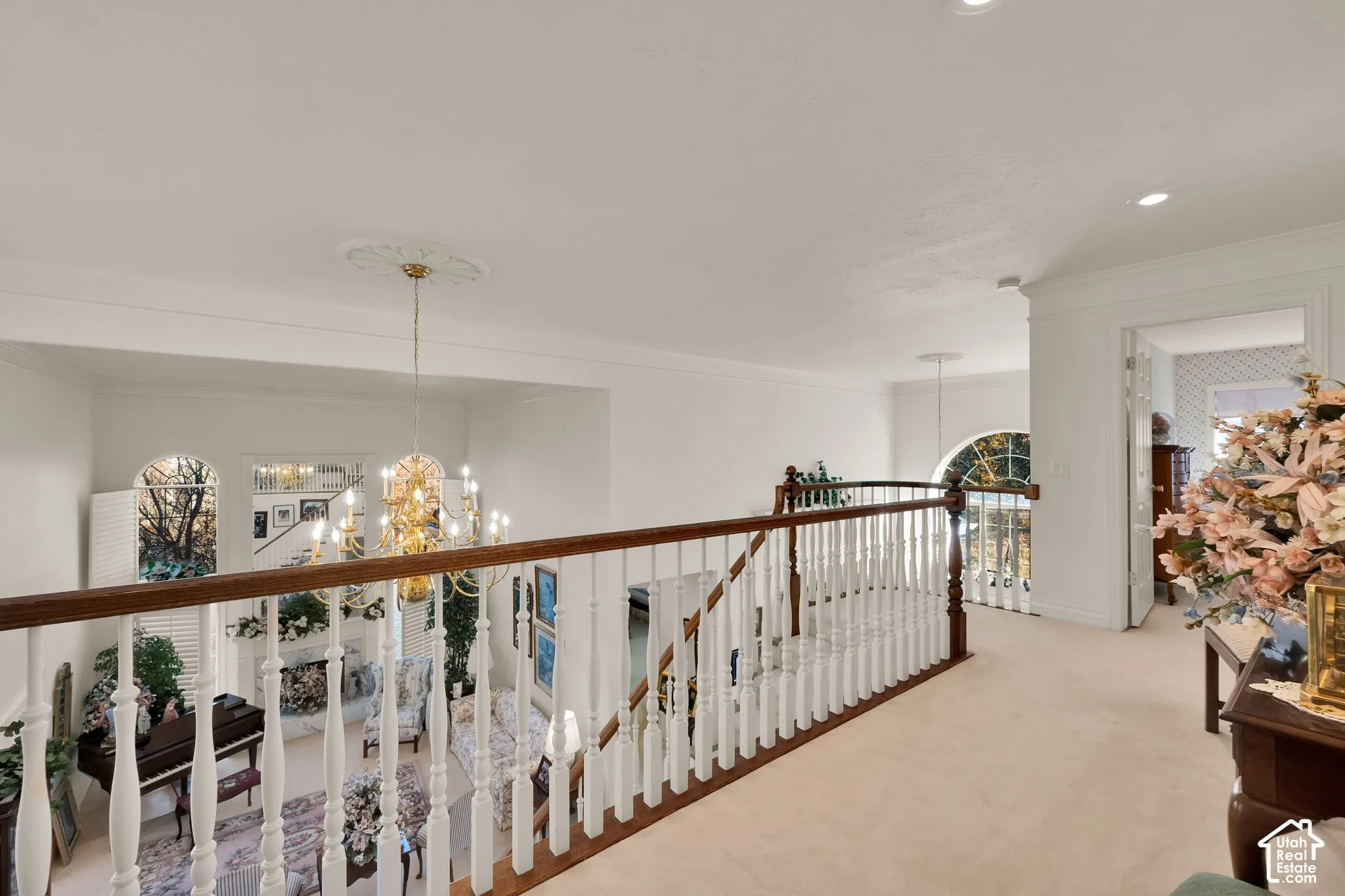 Second-story landing featuring a wooden handrail with white balusters, recessed lighting, arched windows, and crown molding