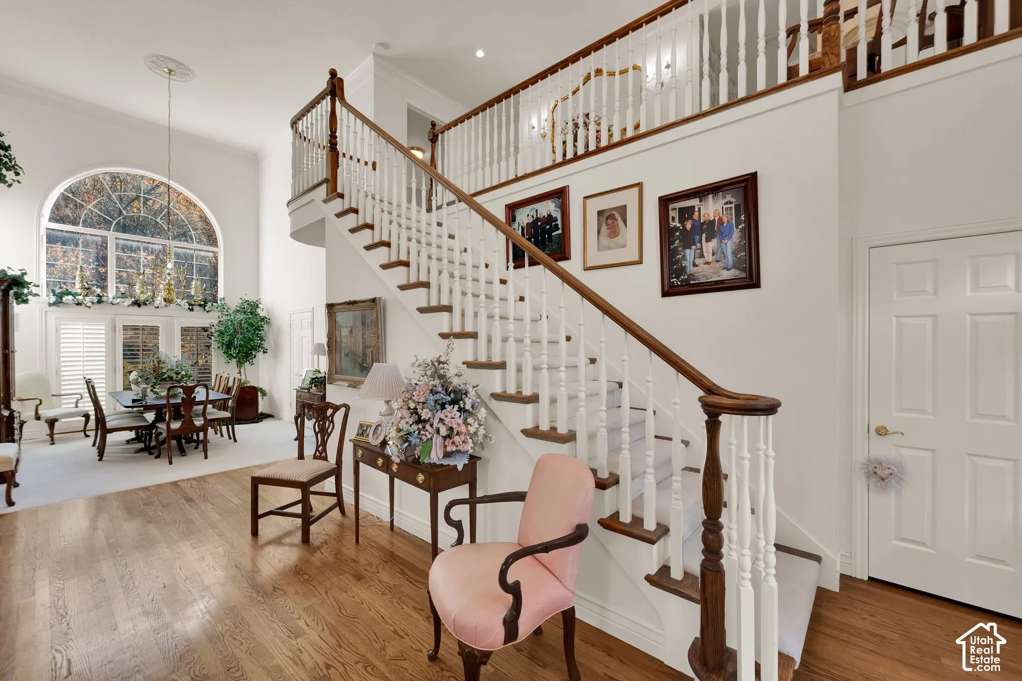 Grand entry featuring a two-story ceiling, arched window, wood-finish flooring, and a staircase with a wooden handrail and white balusters
