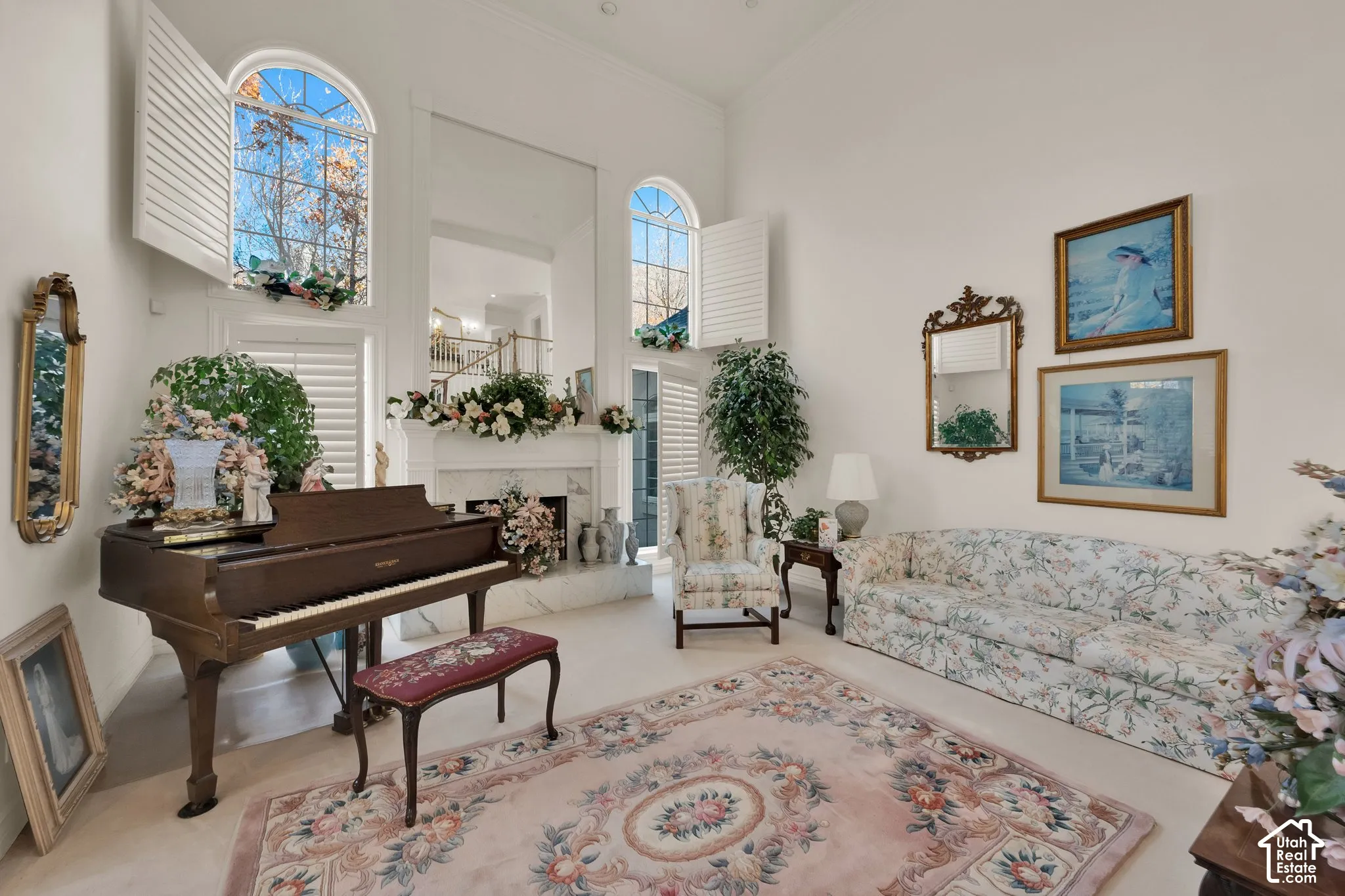 High-ceiling interior featuring arched windows, plantation shutters, a stone-surround fireplace, and an expansive wall mirror
