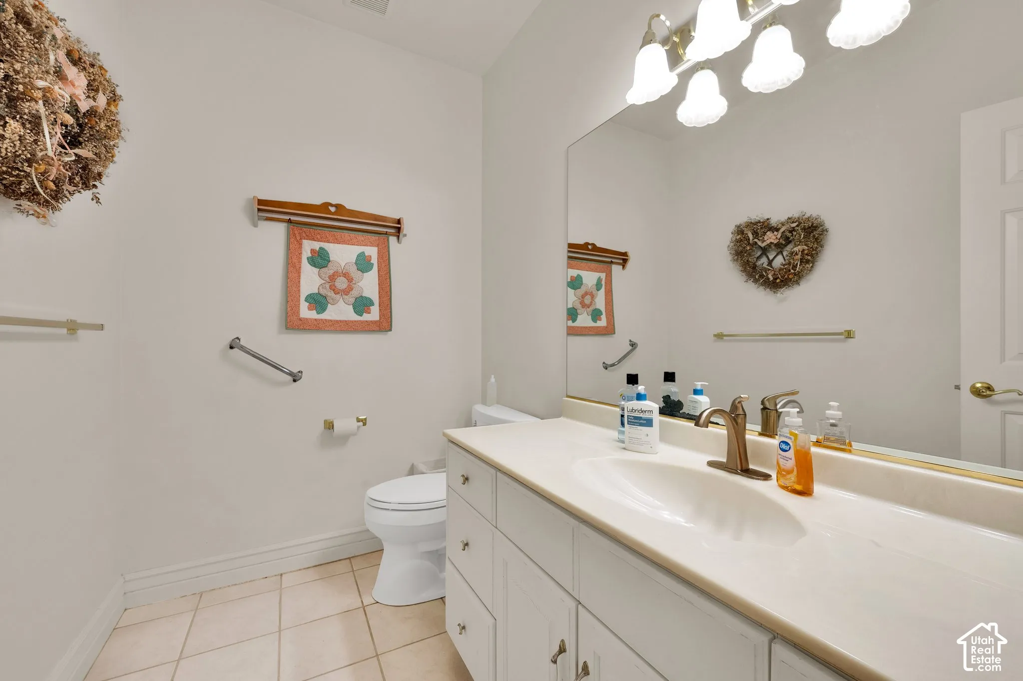 Bathroom featuring a vanity with integrated sink, stone-finish countertop, brushed metal faucet, large wall-mounted mirror, and tile flooring