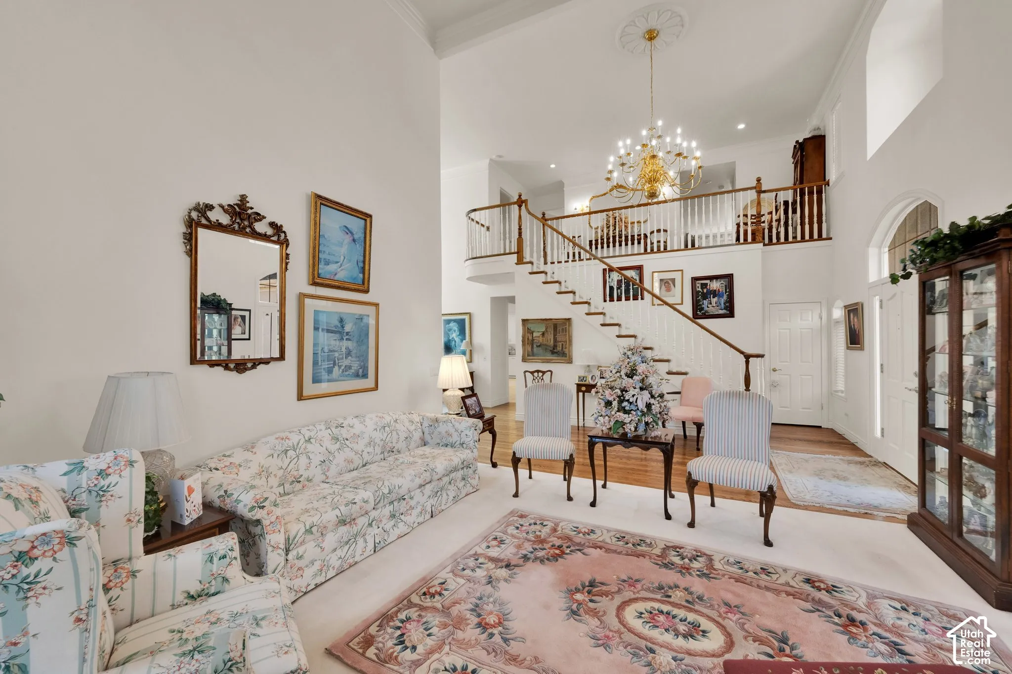 Two-story foyer featuring a staircase with a wooden banister, multi-tiered chandelier with ceiling medallion, high ceilings, and arched entryway