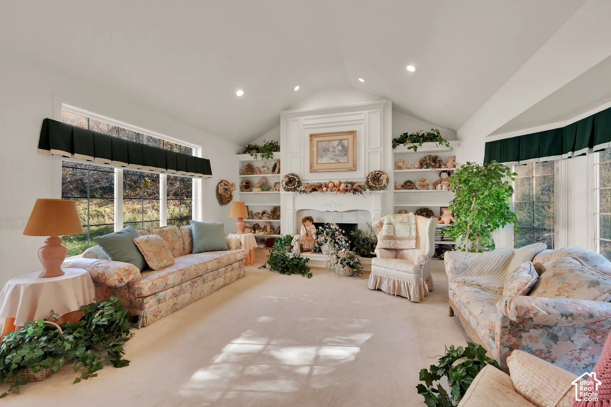 Vaulted ceilings, built-in shelving flanking a central fireplace with decorative millwork, and expansive windows