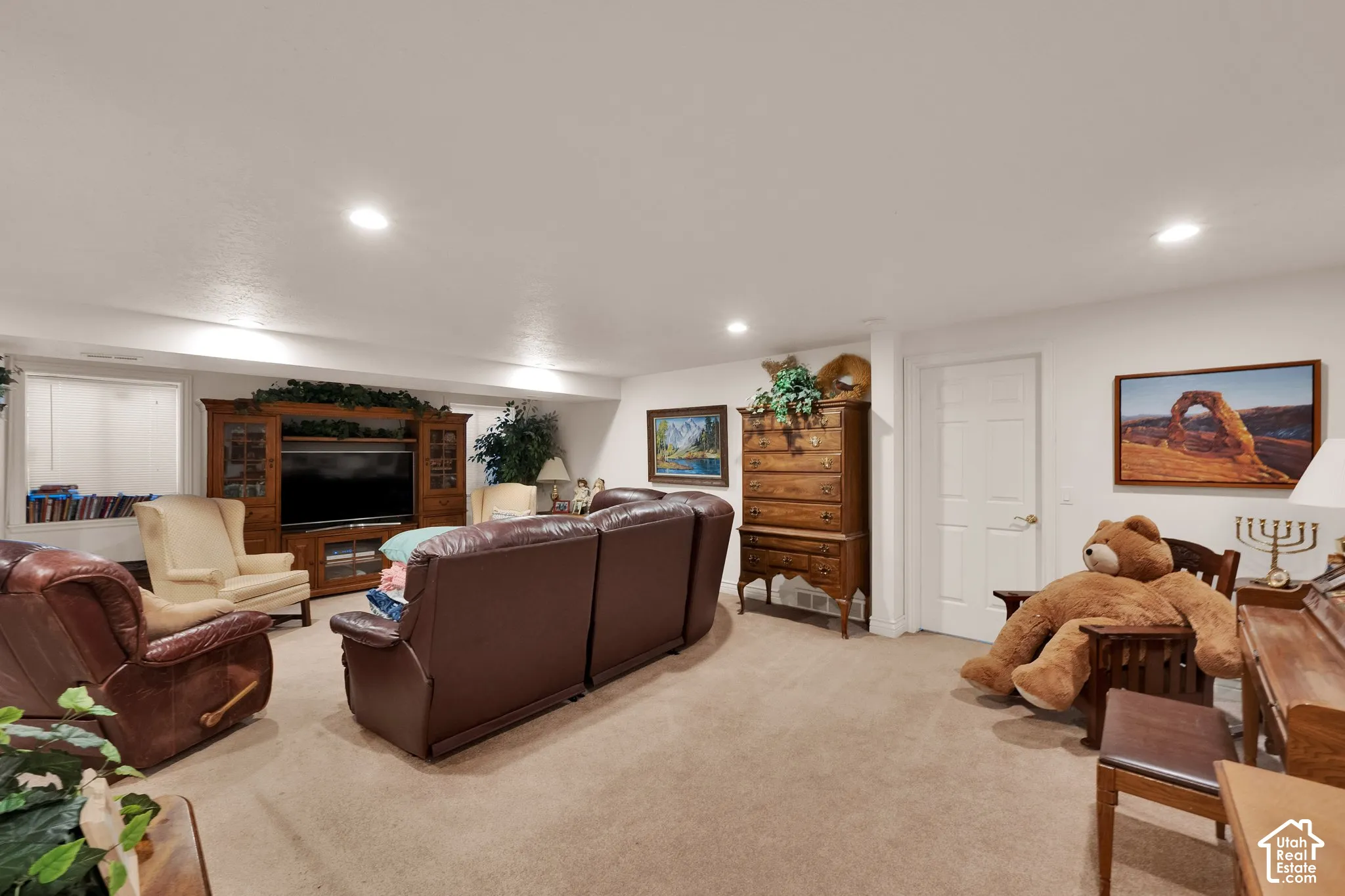 Recessed lighting, neutral carpeting, and built-in wooden media cabinetry