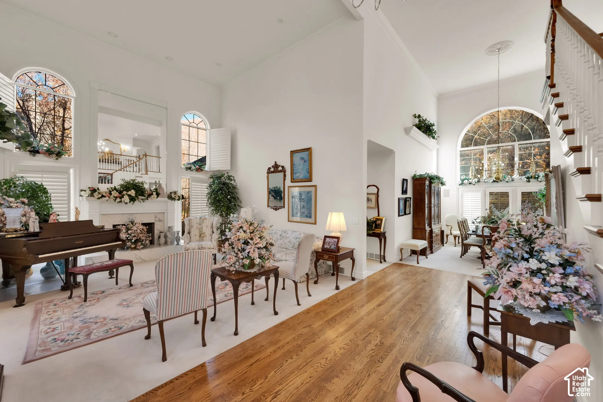 Expansive living area featuring vaulted ceilings, floor-to-ceiling arched windows, wood-finish flooring, and a fireplace with stone surround